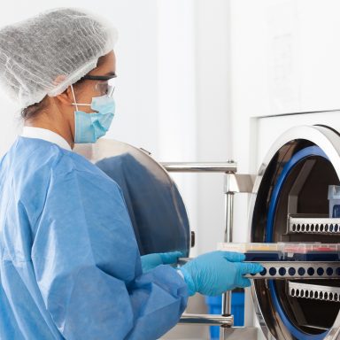 Young female scientist sterilizing laboratory material in autoclave