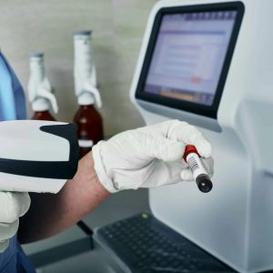Scanning barcode of test tube with blood, hematology analyzer on background, close-up. Medical laboratory